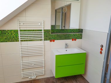 Badezimmer mit Heizkörper und grünen Fliesen